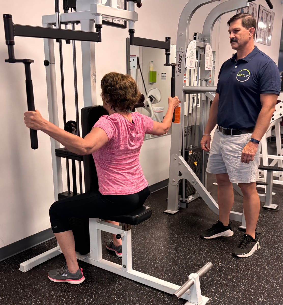 Scott coaching a client on a strength-training machine